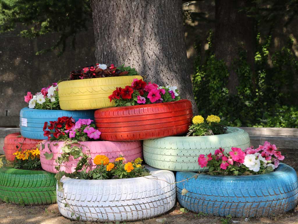 Vieux pneus de voiture Upcyclés et peinturés de différentes couleurs vive et transformer en jardinières à fleurs pour le jardin. Pour mettre en lumière les options infinis du upcycling.